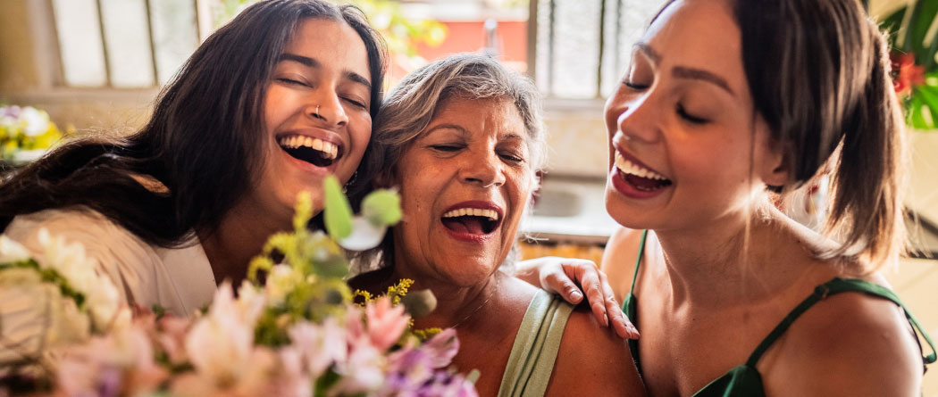 two young women and a mature woman holding a bouquet of flowers together