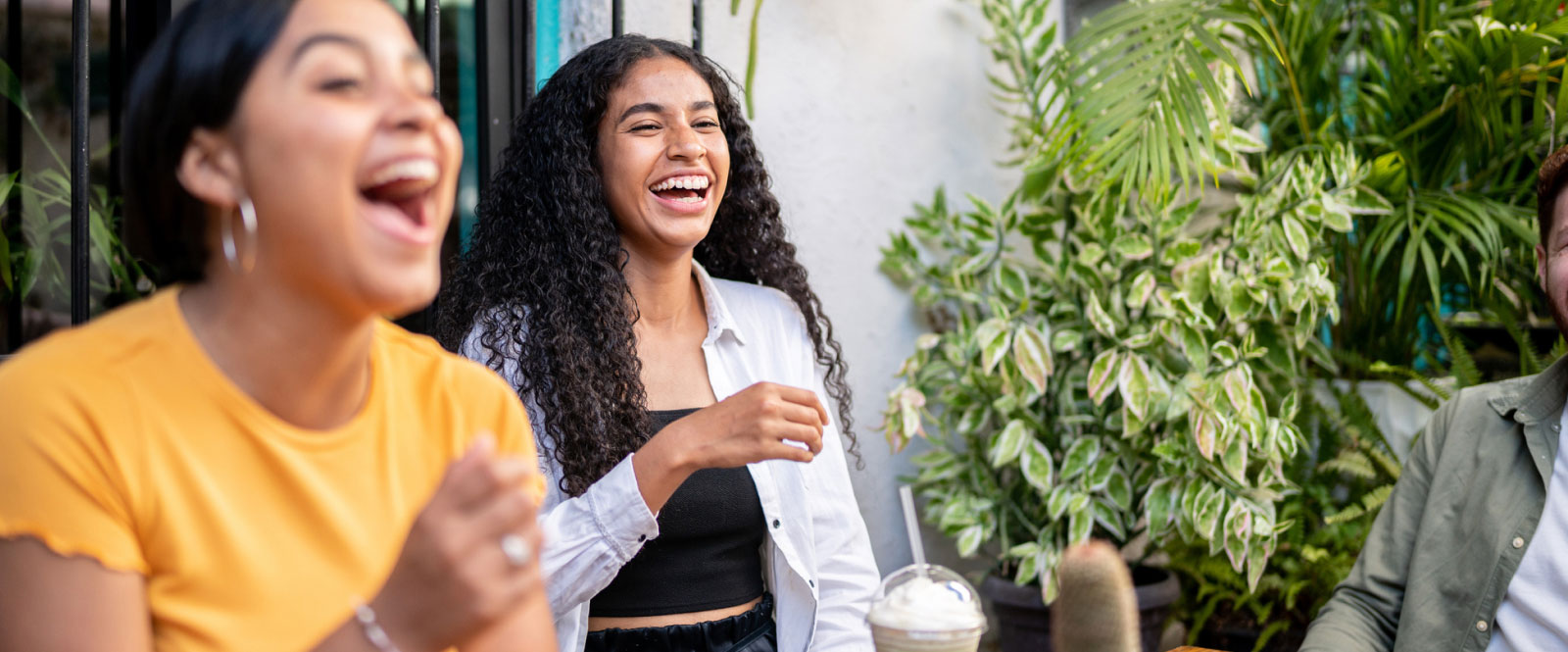group of young adults laughing together outside on a patio 
