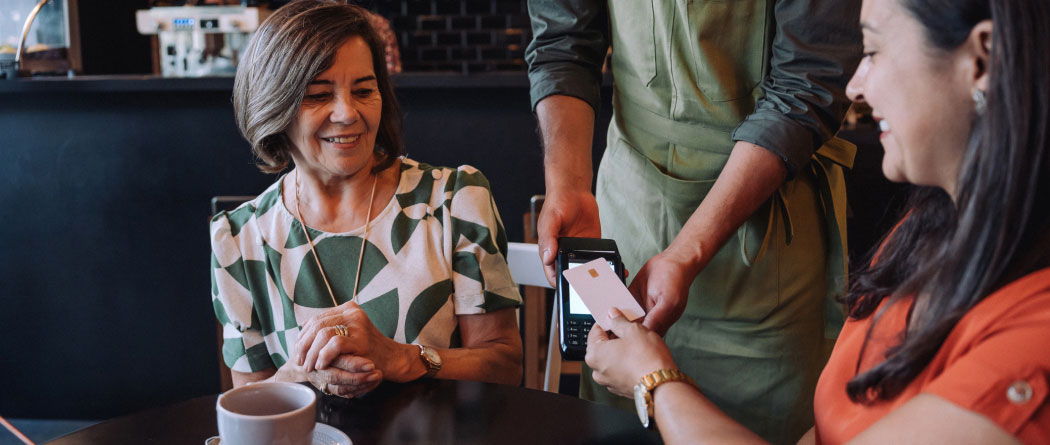 two women paying for their food at a cafe using a credit card